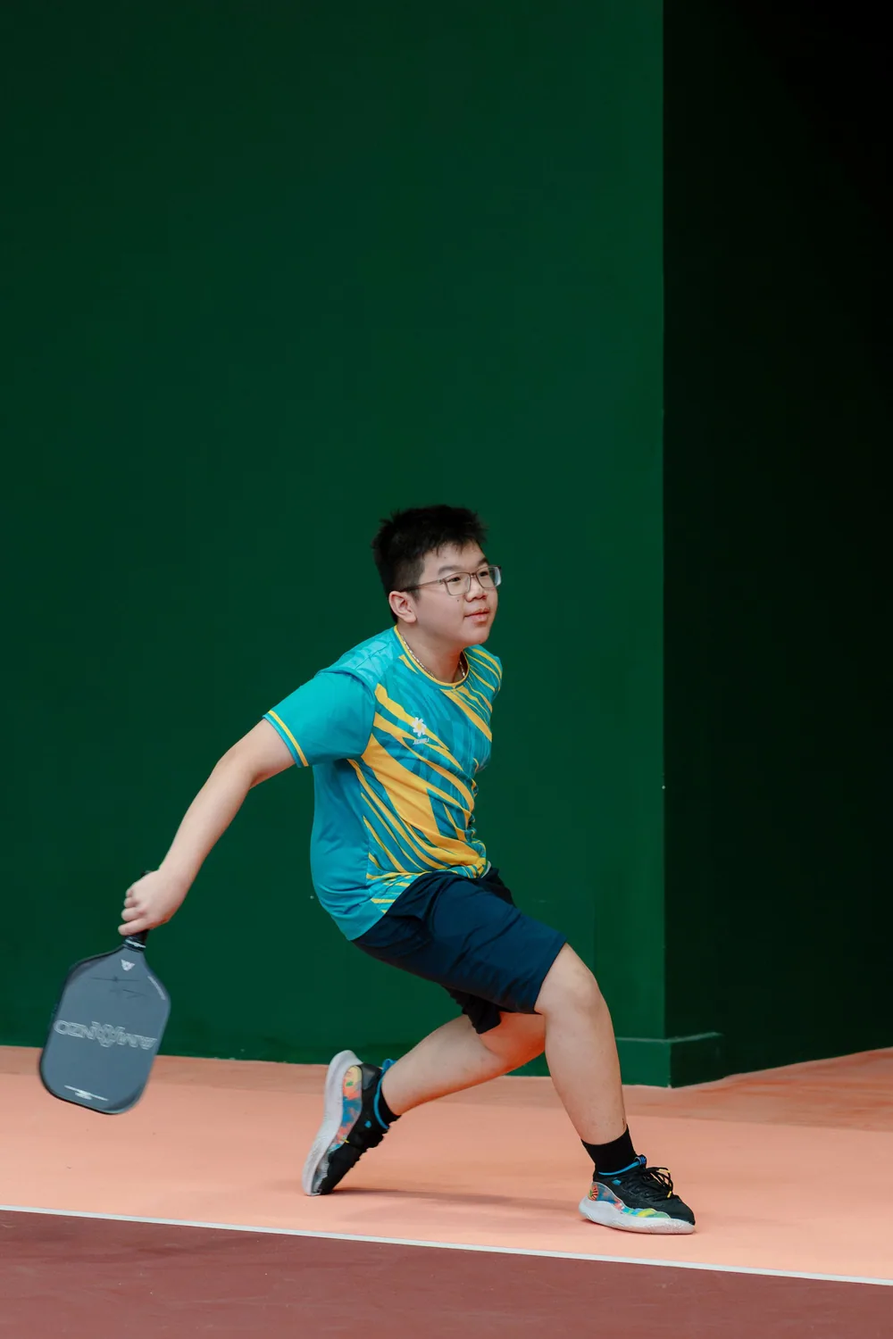 Young player lunging for a shot during a junior pickleball session